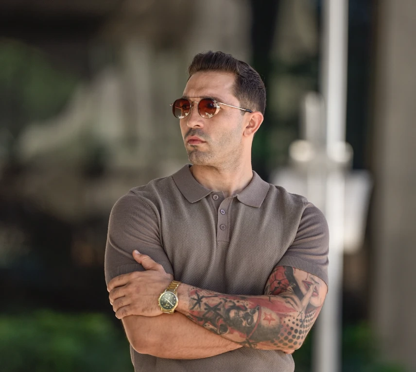 Lucas Reis, fundador da Levon Clothing e embaixador da ConneIA, de óculos escuros e camisa polo, com os braços cruzados